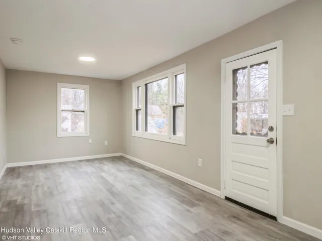 a view of an empty room with a window and wooden floor
