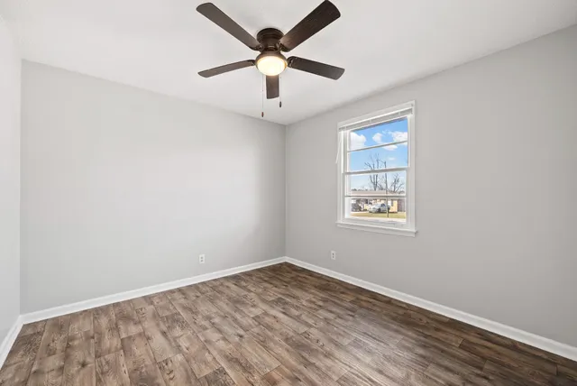 an empty room with a window and a fan