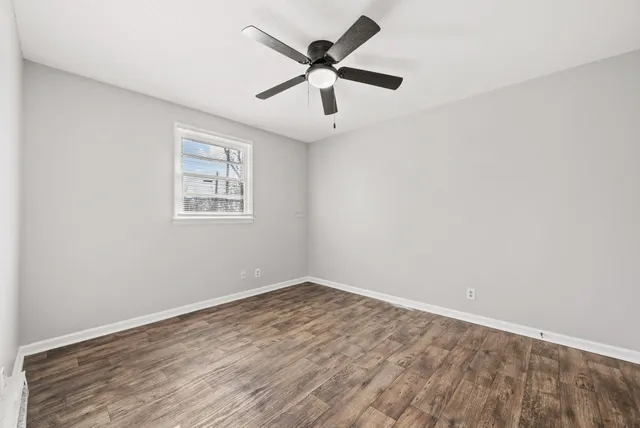 an empty room with wooden floor and ceiling fan