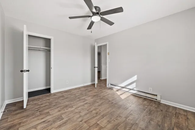 an empty room with wooden floor and a ceiling fan
