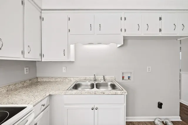 a kitchen with granite countertop white cabinets and a sink