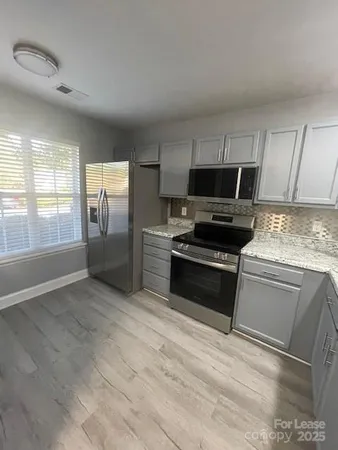 a kitchen with granite countertop a stove a sink and a refrigerator