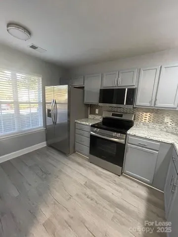 a kitchen with granite countertop a stove a sink and a refrigerator