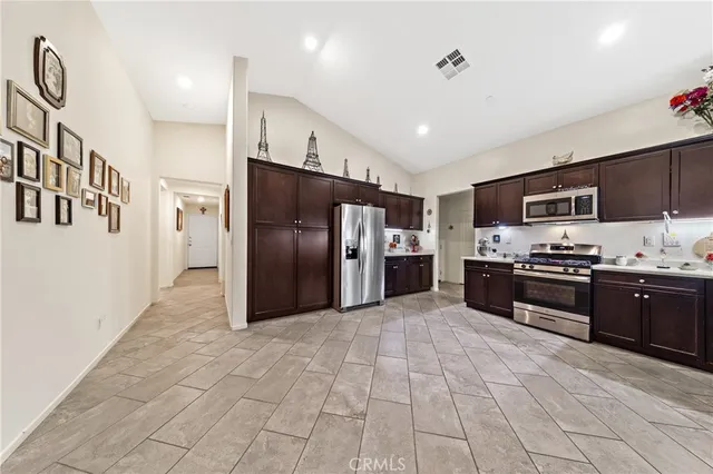 a large kitchen with stainless steel appliances kitchen island granite countertop a refrigerator and a stove top oven