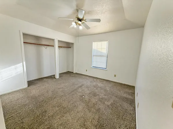 an empty room with windows and fan