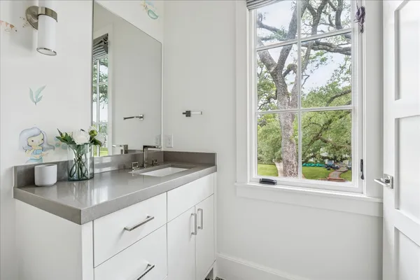 a bathroom with a granite countertop sink and a window
