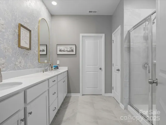 a spacious bathroom with a double vanity sink a mirror and a shower