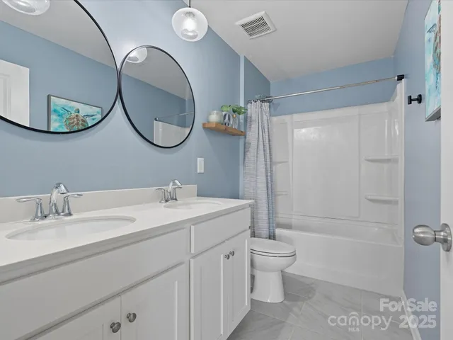 a bathroom with a double vanity sink toilet mirror and shower