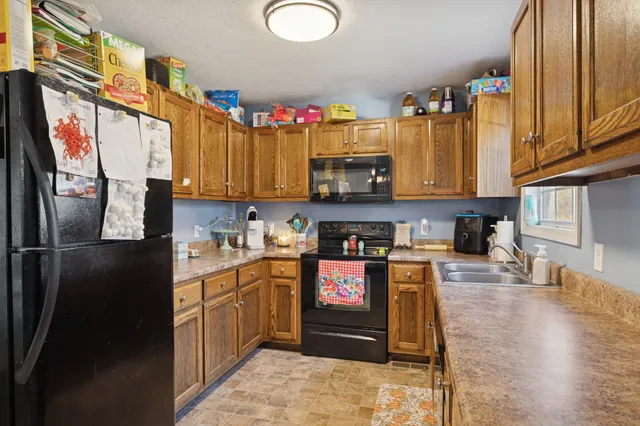 a kitchen with stainless steel appliances granite countertop a refrigerator a stove top oven and sink with wooden floor