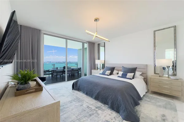 a bedroom with a bed flat screen tv and a large window