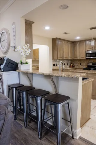 a kitchen with stainless steel appliances kitchen island granite countertop a table chairs sink and cabinets