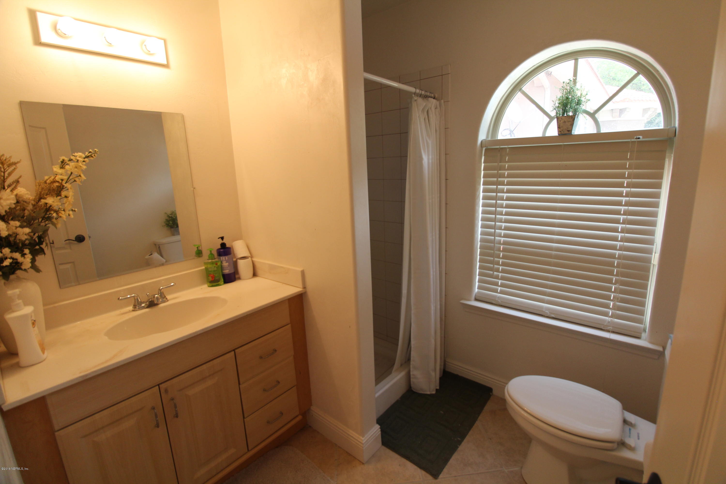 6471 Immokalee Road Keystone Heights, FL 32656 - Photo 83 of 103 a bathroom with a toilet a sink a mirror a window and vanity