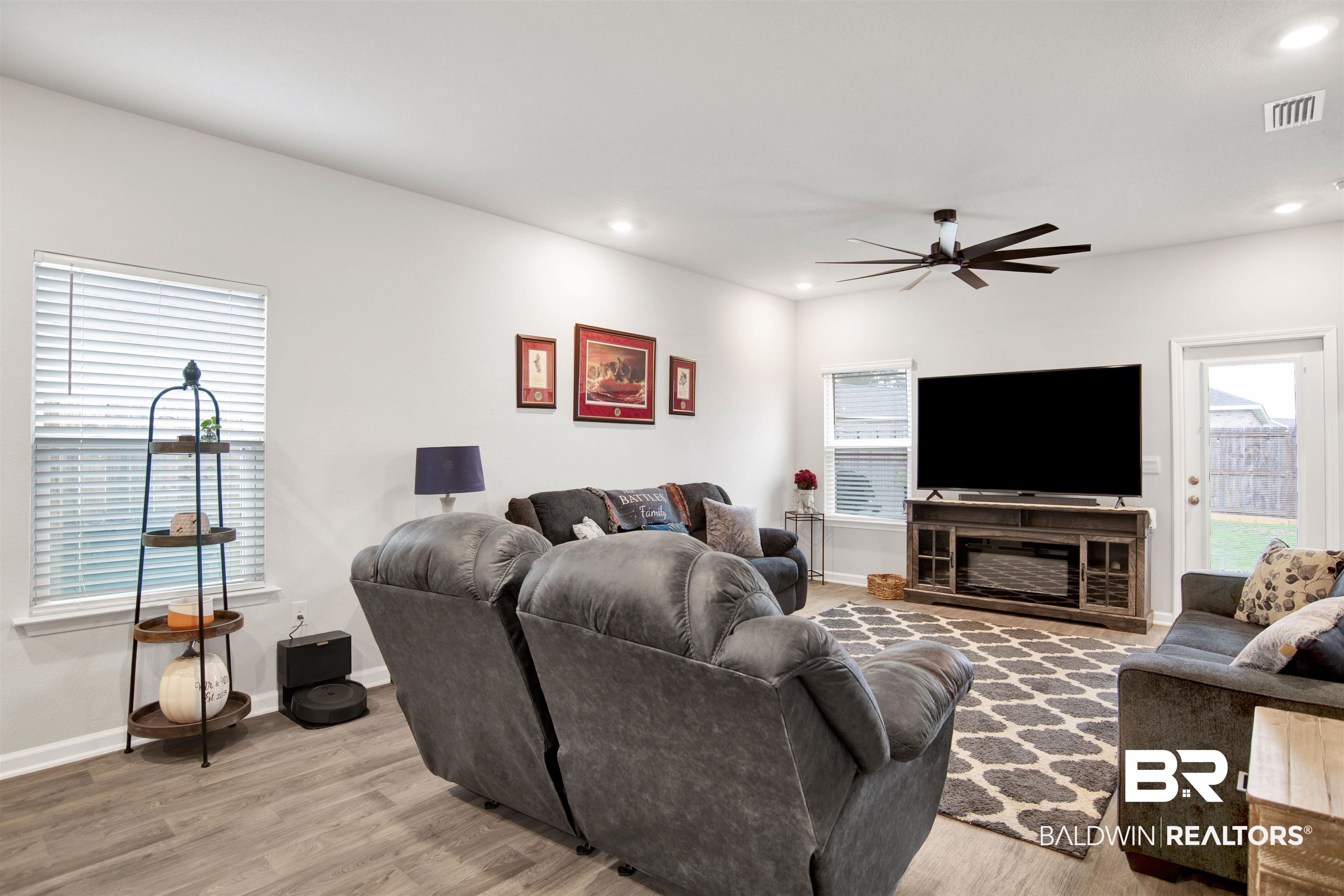 12813 Patriot Way Daphne, AL 36527 - Photo 7 of 23 Spacious living area featuring wood-finish flooring, a contemporary ceiling fan, recessed lighting, multiple windows with blinds, and a built-in media console with an integrated electric fireplace