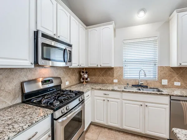 a kitchen with granite countertop a stove sink and cabinets