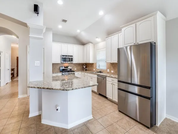 a kitchen with kitchen island granite countertop stainless steel appliances and refrigerator