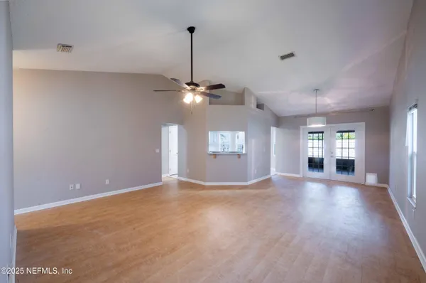a view of an empty room with window and wooden floor