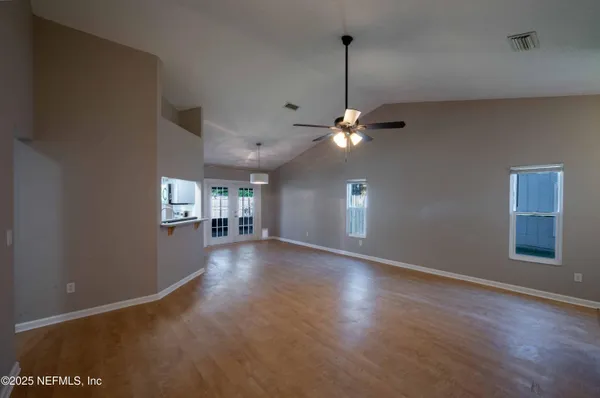 a view of an empty room with window and wooden floor