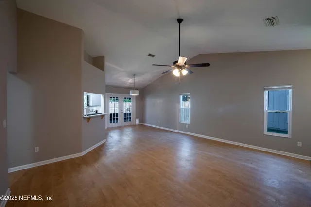 a view of an empty room with window and wooden floor