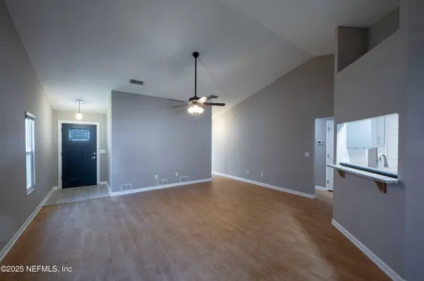 an empty room with chandelier fan and windows