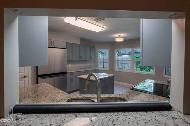 a view of kitchen with stainless steel appliances granite countertop sink and refrigerator