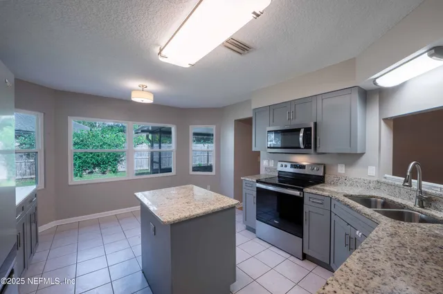 a kitchen with granite countertop a stove sink and microwave