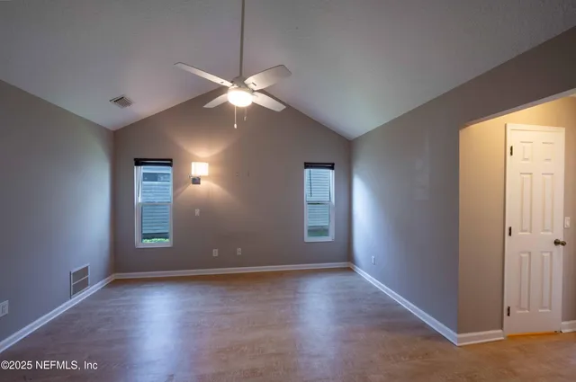 an empty room with wooden floor and windows