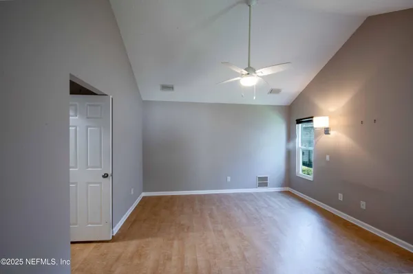 a view of empty room with wooden floor and fan