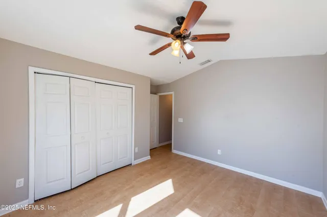 an empty room with ceiling fan and windows