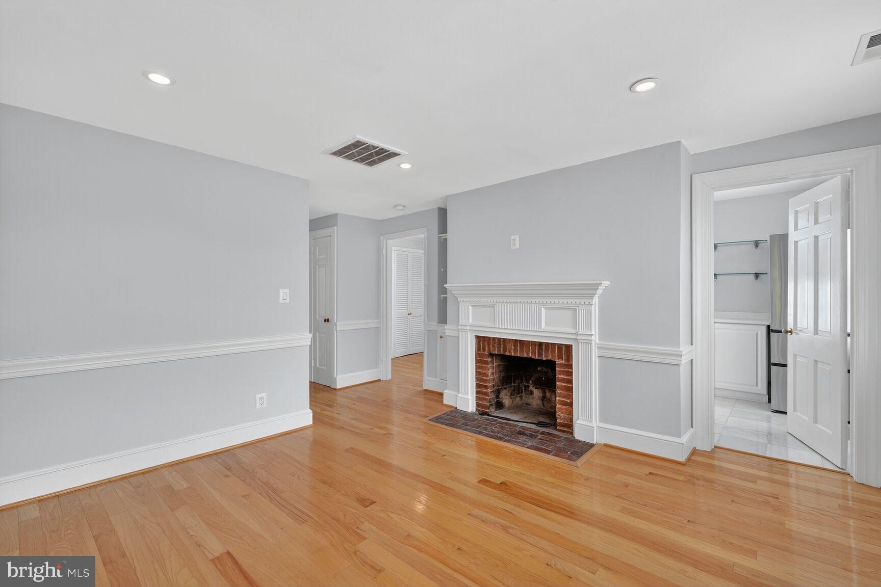 1363 28th Street Northwest, Unit 3 Washington, DC 20007 - Photo 7 of 13 a view of an empty room with wooden floor fireplace and a window