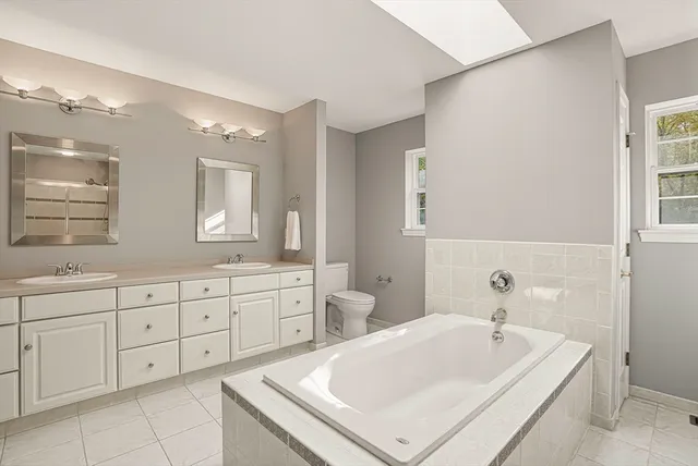 a spacious bathroom with a tub sink and mirror