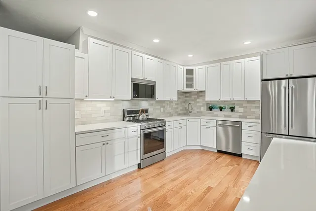 a kitchen with a white cabinets and wooden floor