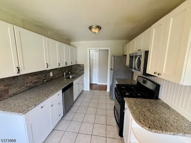 a kitchen with granite countertop a sink a stove and refrigerator