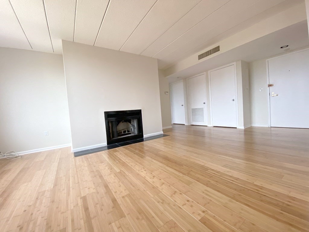 85 Brainerd Road, Unit 503 Boston, MA 02134 - Photo 4 of 21 a view of empty room with wooden floor and fireplace