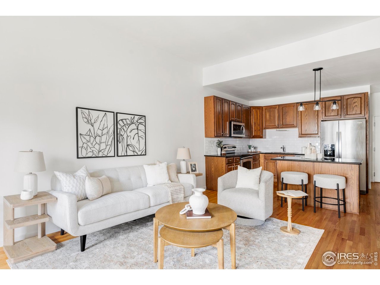 a living room with furniture kitchen view and a wooden floor