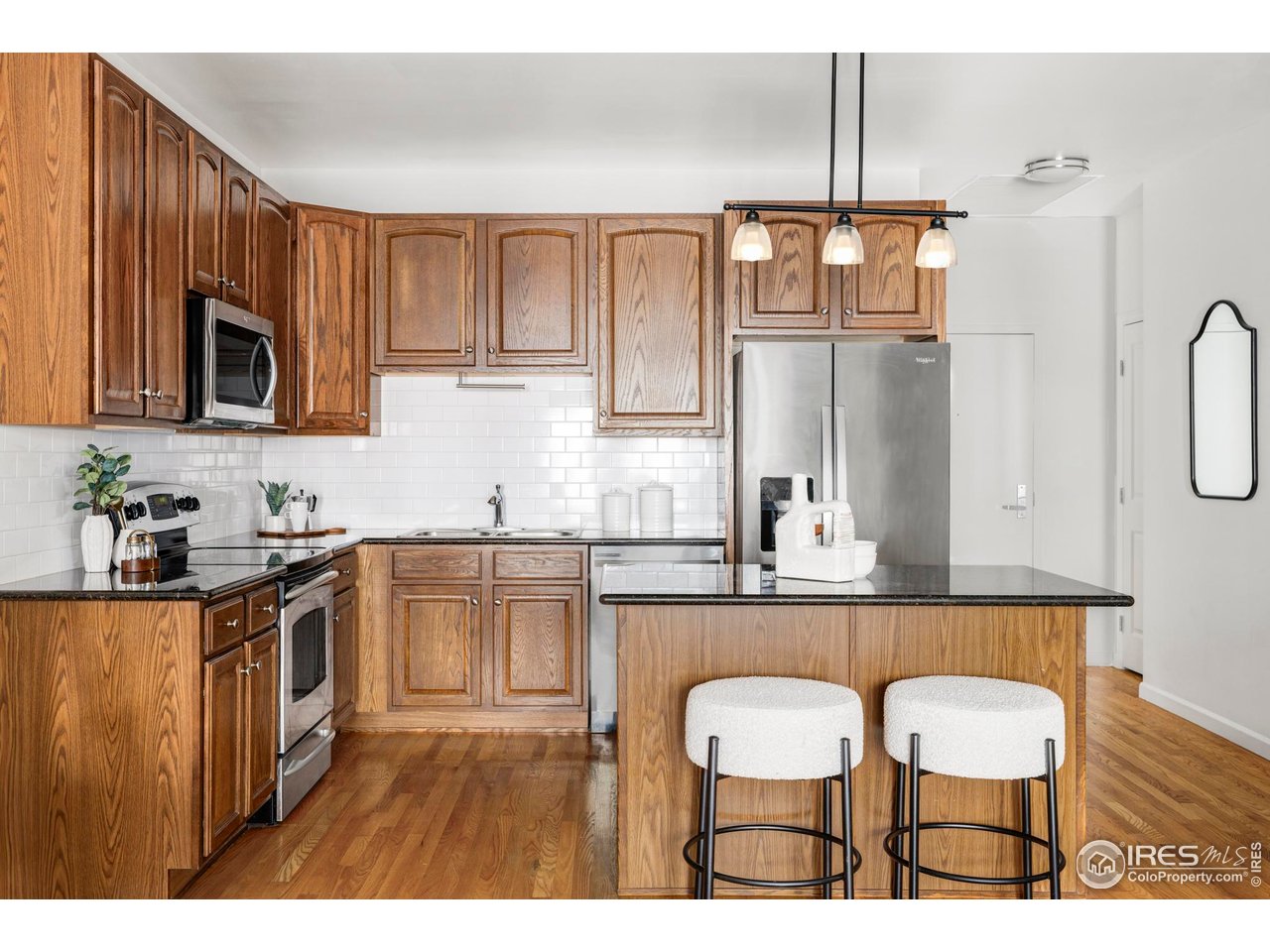 1950 Logan Street, Unit 1013 Denver, CO 80203 - Photo 3 of 23 a kitchen with kitchen island granite countertop a sink cabinets and stainless steel appliances