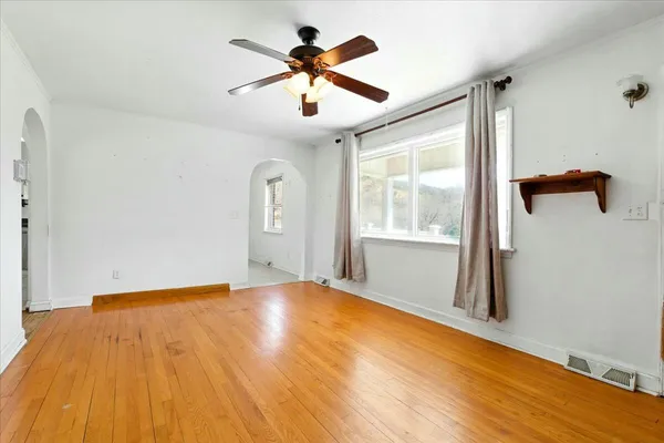 a view of an empty room with window and wooden floor