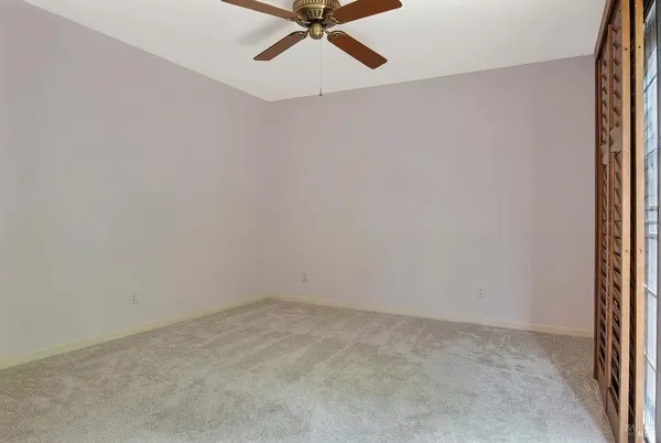 an empty room with a ceiling fan and carpet