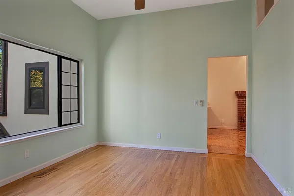 a view of an empty room with wooden floor and a window