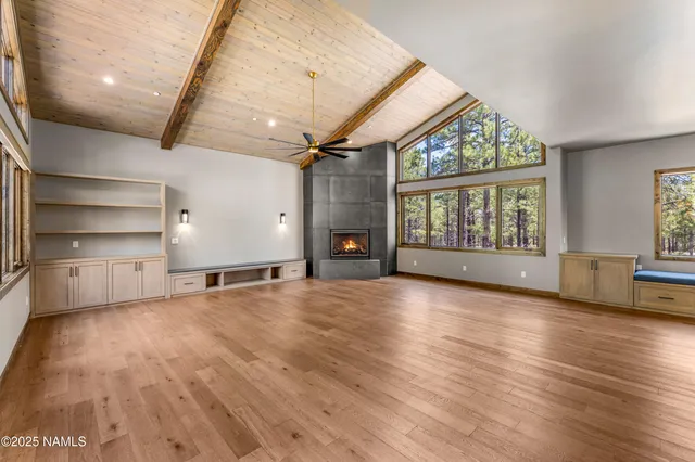 an empty room with windows ceiling fan and fireplace