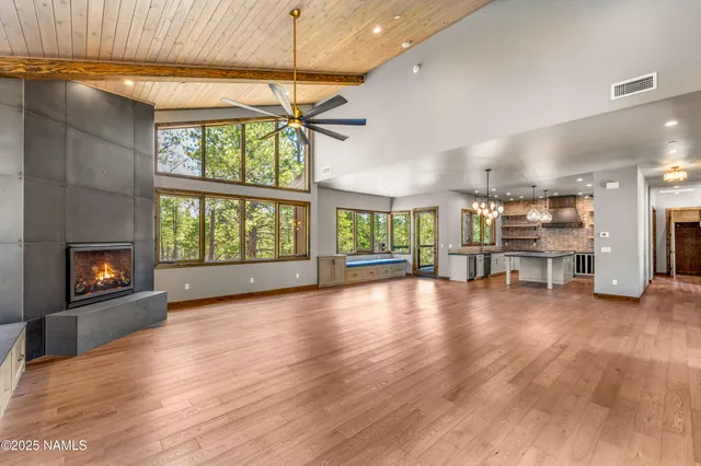 a view of a kitchen with stainless steel appliances granite countertop a refrigerator a sink dishwasher a stove and white cabinets with wooden floor