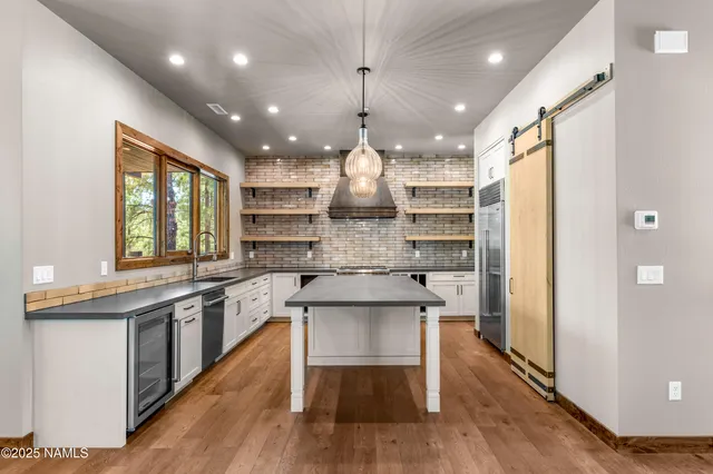 a kitchen with kitchen island a large counter top appliances and a window