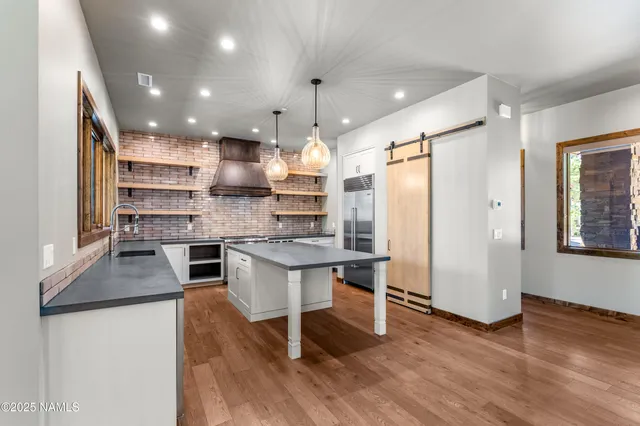 a large kitchen with kitchen island a large counter space a large window and stainless steel appliances