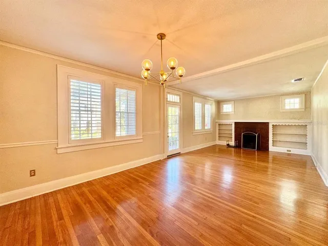 a view of empty room with wooden floor and fireplace
