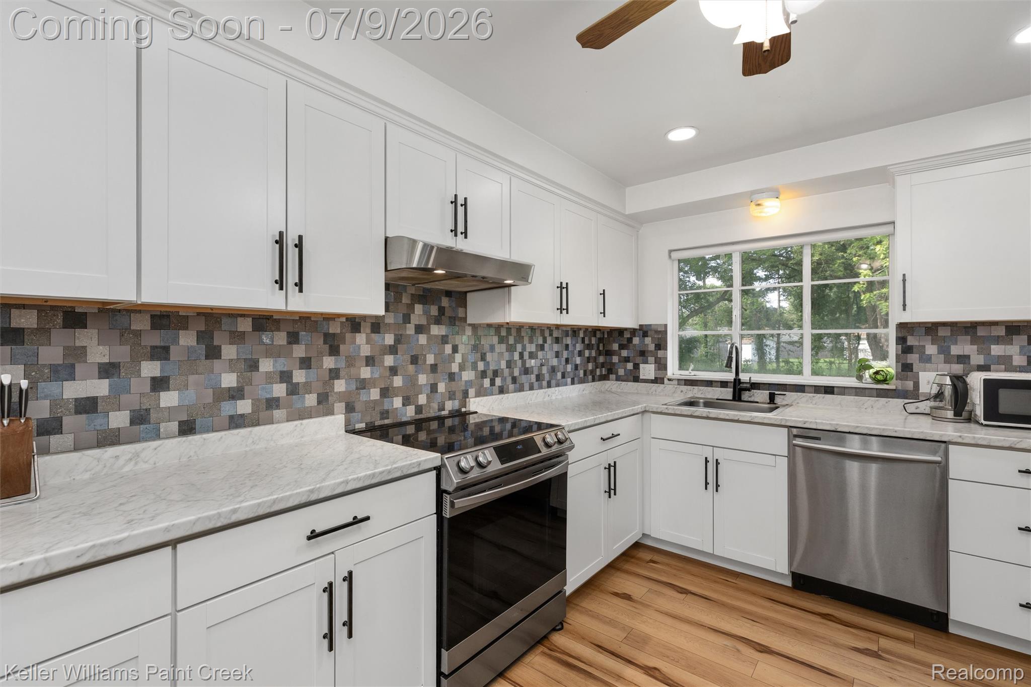 2731 Crooks Road Royal Oak, MI 48073 - Photo 13 of 34 Kitchen featuring white shaker-style cabinetry, mosaic tile backsplash, light-toned countertops, stainless steel appliances, and wood-finish flooring