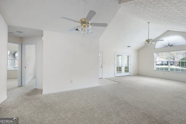 an empty room with windows and chandelier fan
