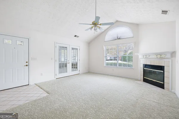 an empty room with windows fireplace and fan