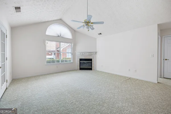 an empty room with windows fireplace and fan