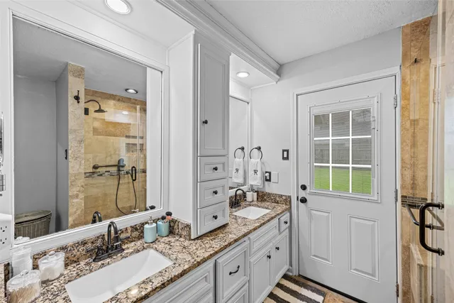 a bathroom with a granite countertop double vanity sink a mirror and a bathtub