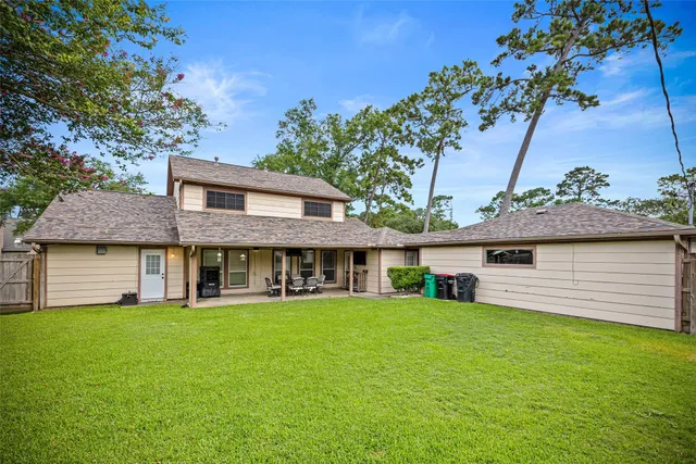 a view of a house with a yard and a large tree