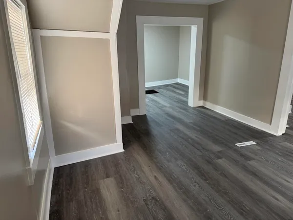 an empty room with wooden floor and entrance